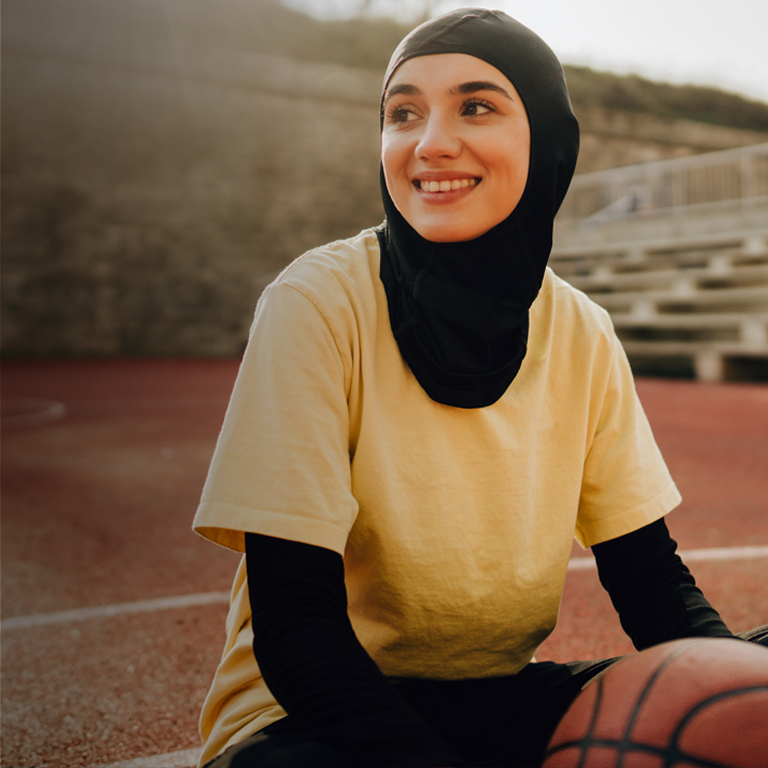 Young woman wearing a hijab playing basketball