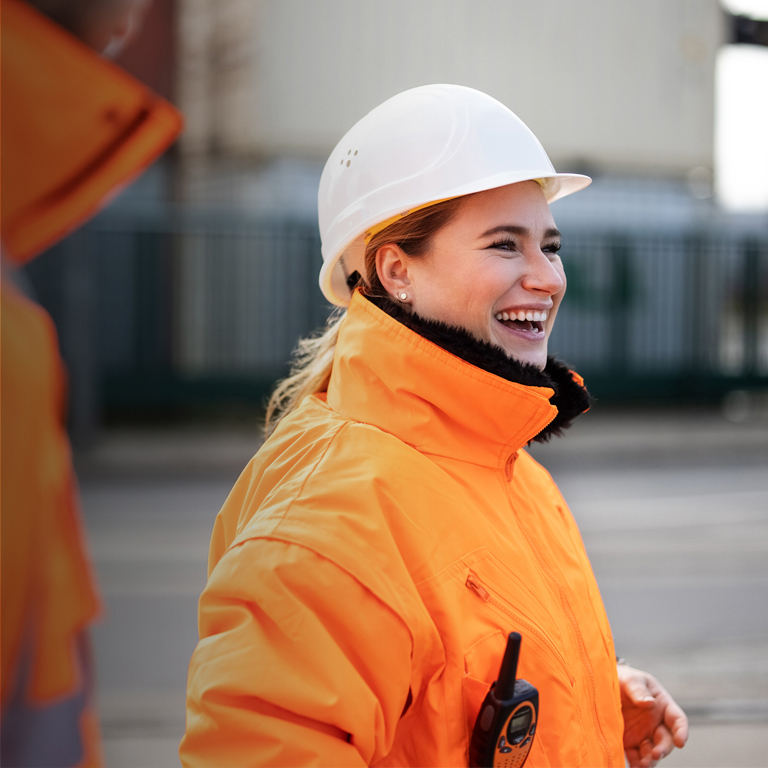 Young woman wearing a protective hard had and high visibility jacket while working