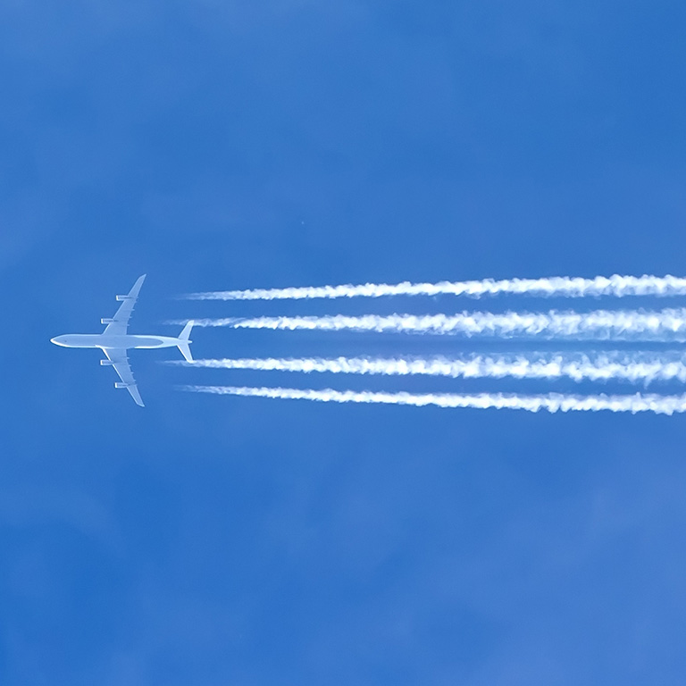 Airplane with contrails in a clear blue sky, Cruising altitude