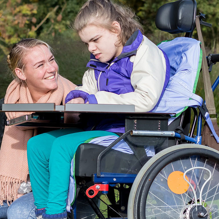 Disabled girl relaxing outside / disabled girl relaxing outside together with a care assistant