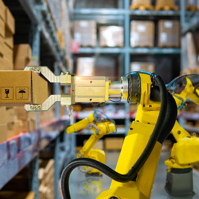 Robotic arm lifting a package in a warehouse.