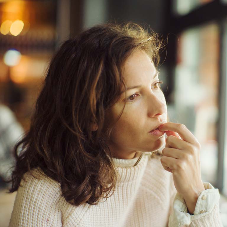 Beautiful thoughtful lady in bar, with finger in mouth.