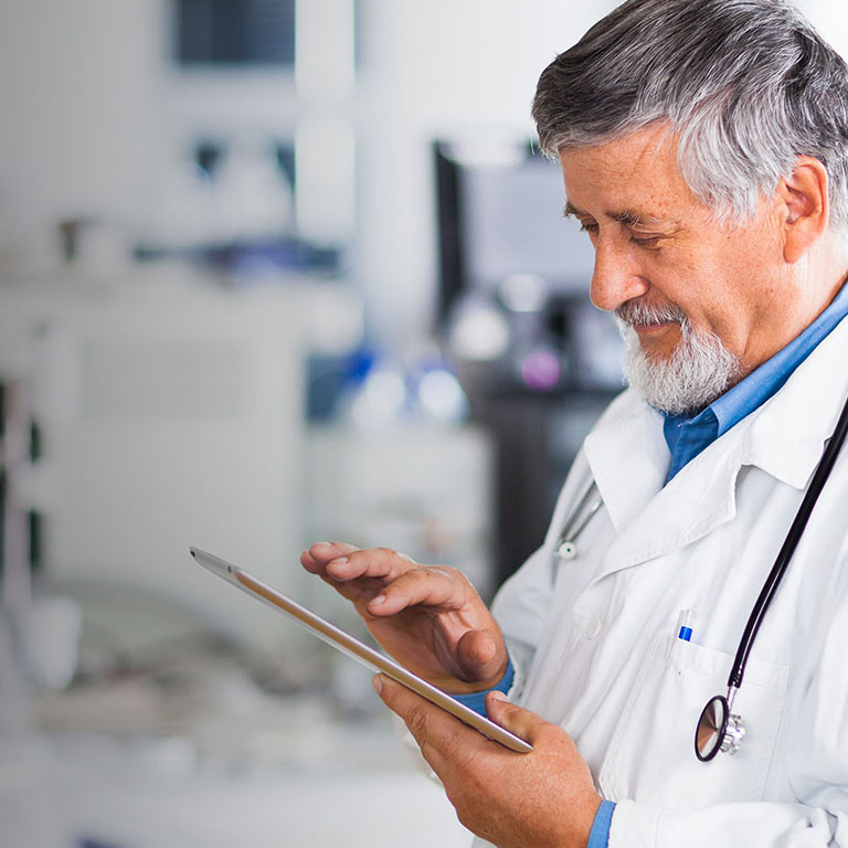 Senior doctor using his tablet computer at work (color toned image)