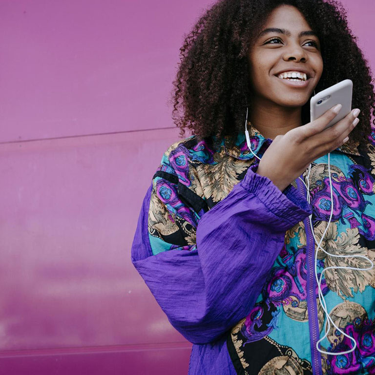 Happy young African woman in a fashionable jacket on a smartphone
