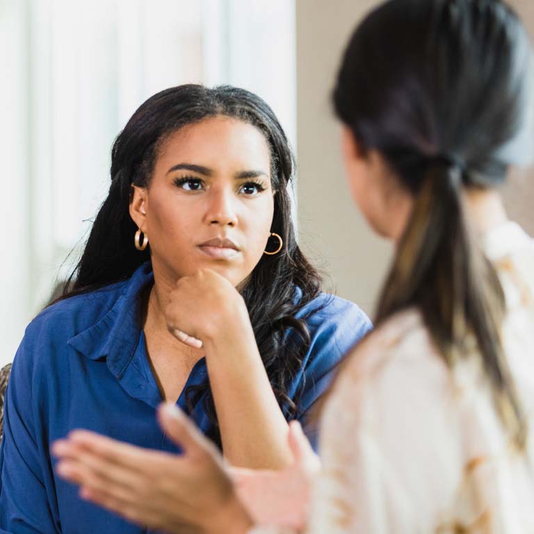 During a counseling session, the  unrecognizable mid adult female patient gestures while speaking.  The mid adult female therapist listens attentively.