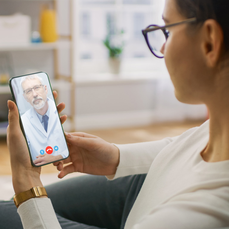 Young Girl Sick at Home Using Smartphone to Talk to Her Doctor via Video Conference Medical App. Woman Checks Possible Symptoms with Professional Physician, Using Online Video Chat Application