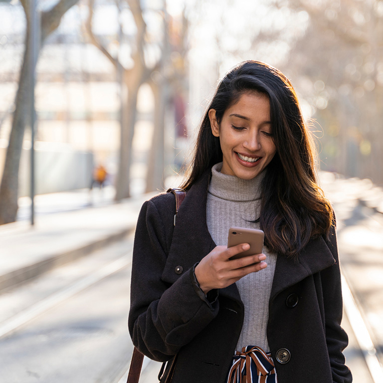 Portrait of smiling young woman with smartphone on tram line