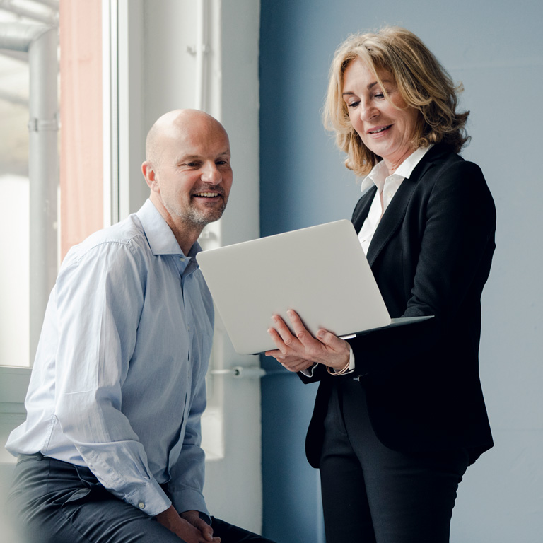 Business director talking to colleague looking at a laptop