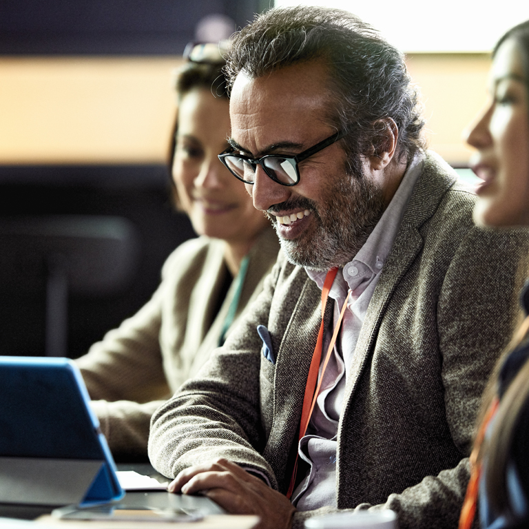 Smiling mature businessman looking at laptop at business meeting with two women