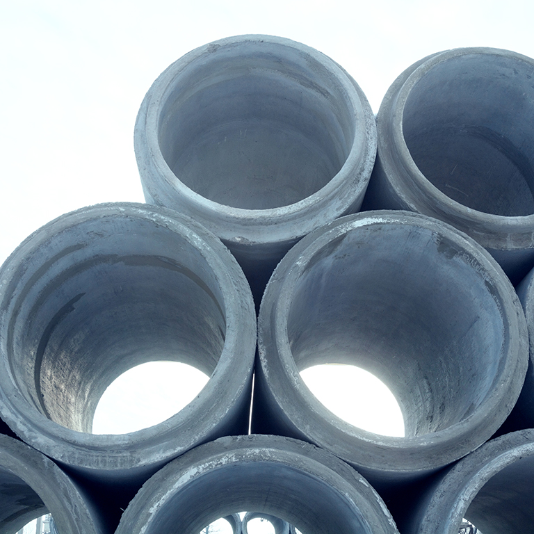 Stack of new concrete pipes. Pipeline construction. Construction material.