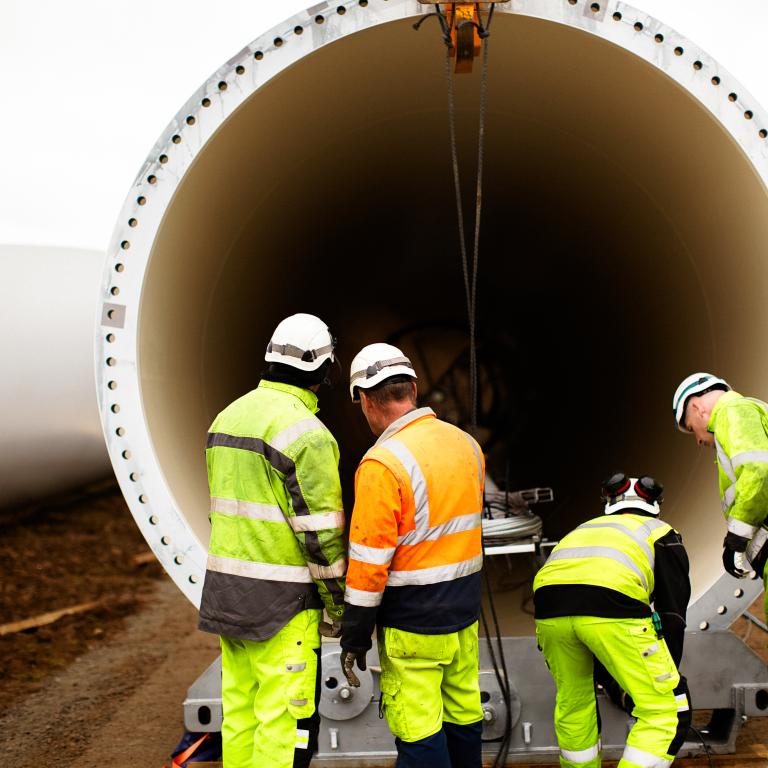 Workers prepare large cylindrical structure on construction site