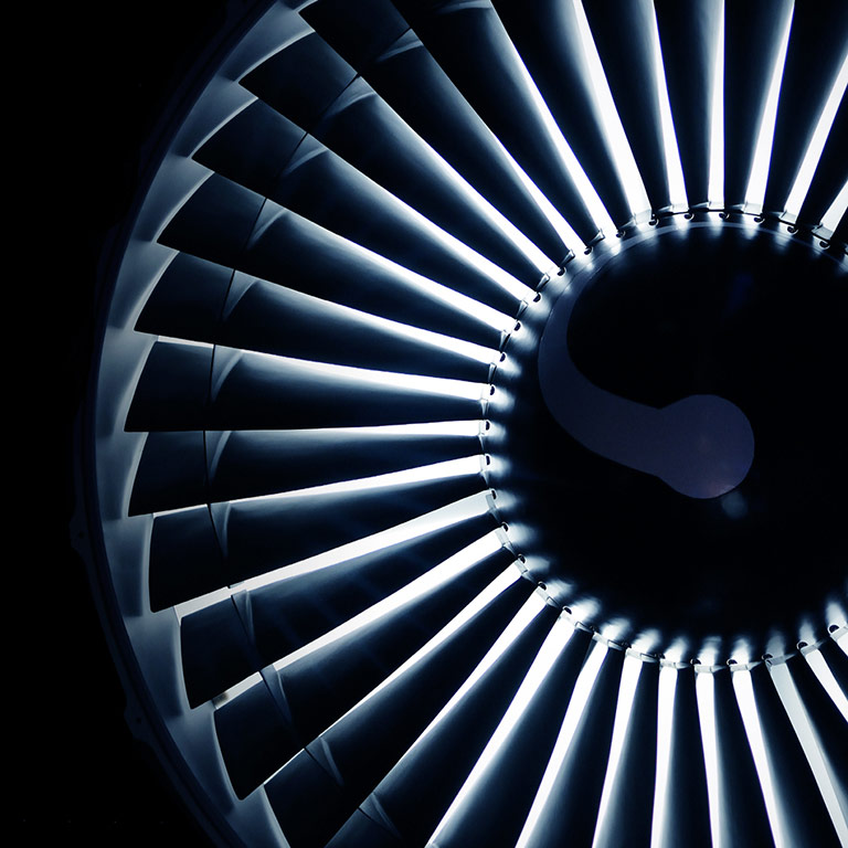 A dark background with a close up crop of a jet engine