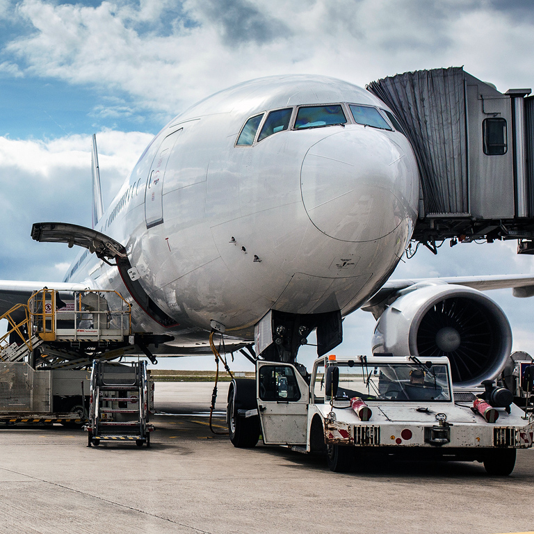 The white unbranded plane at the airport takes passengers through a telescopic ladder. Gound handling.