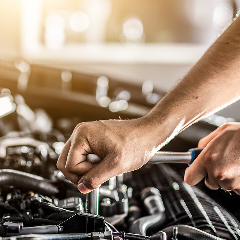 Auto mechanic working and repair on car engine in mechanics garage. Car service. Man with wrench at workshop.