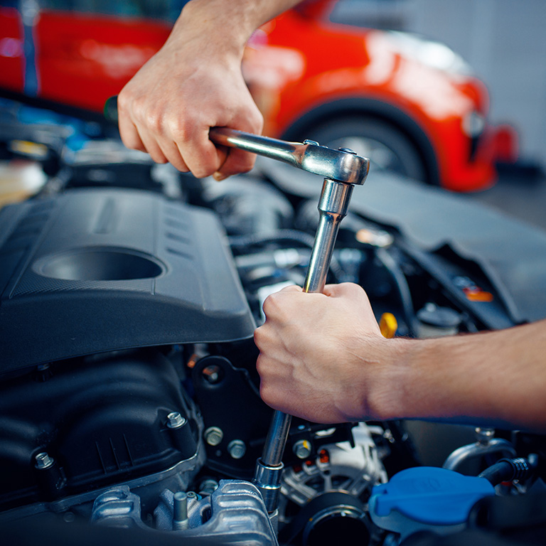 Worker in uniform disassembles vehicle engine, car service station. Automobile checking and inspection, professional diagnostics and repair