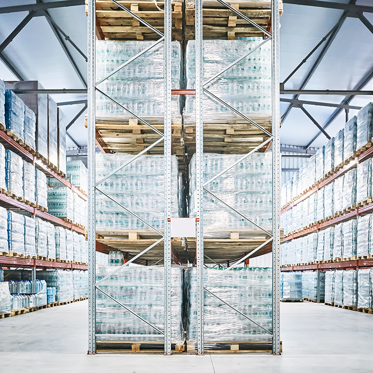 Hangar warehouse with rows of shelves with transparent plastic bags with ready-made factory production of bottled mineral water.