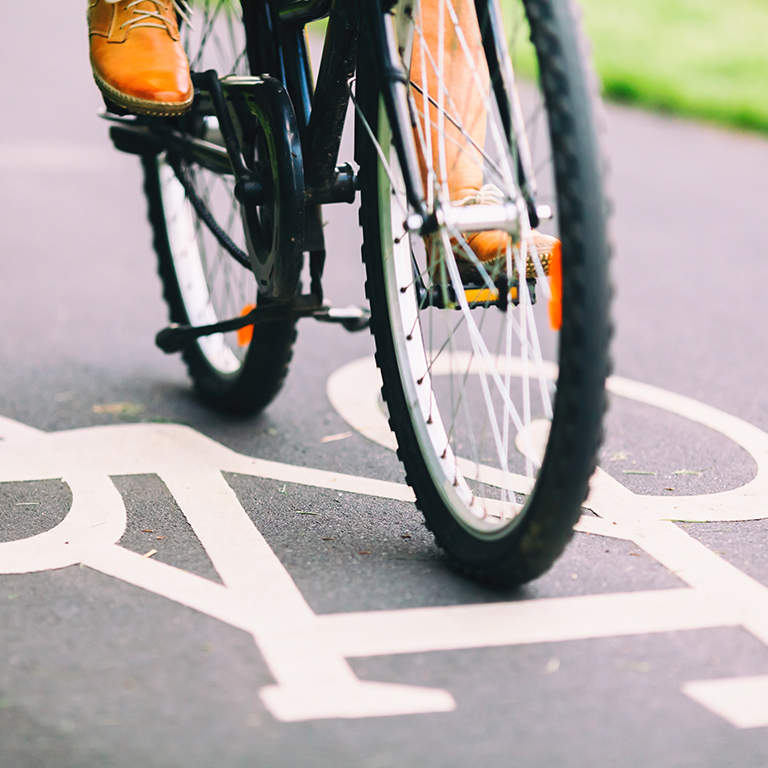 City bike sign on asphalt bikepath man cycling on road, colorful vintage light on street, commuting to work on bicycle in urban environment