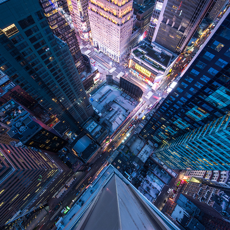 Bird's eye view of Manhattan, looking down at people and yellow taxi cabs going down 5th Avenue. Toned, Instagram photography with slight vignette.