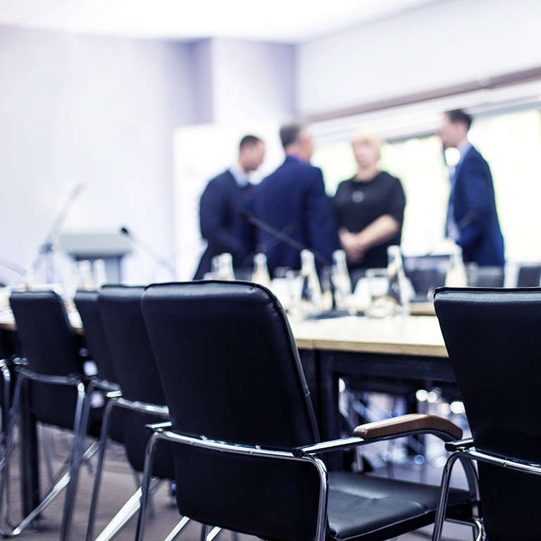 Bottles of water and glasses on the empty meeting table and people in the background. Business concept