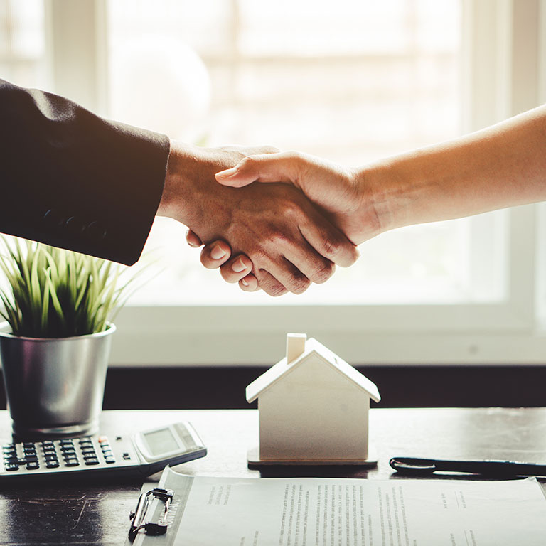 Broker and client shaking hands after signed documents