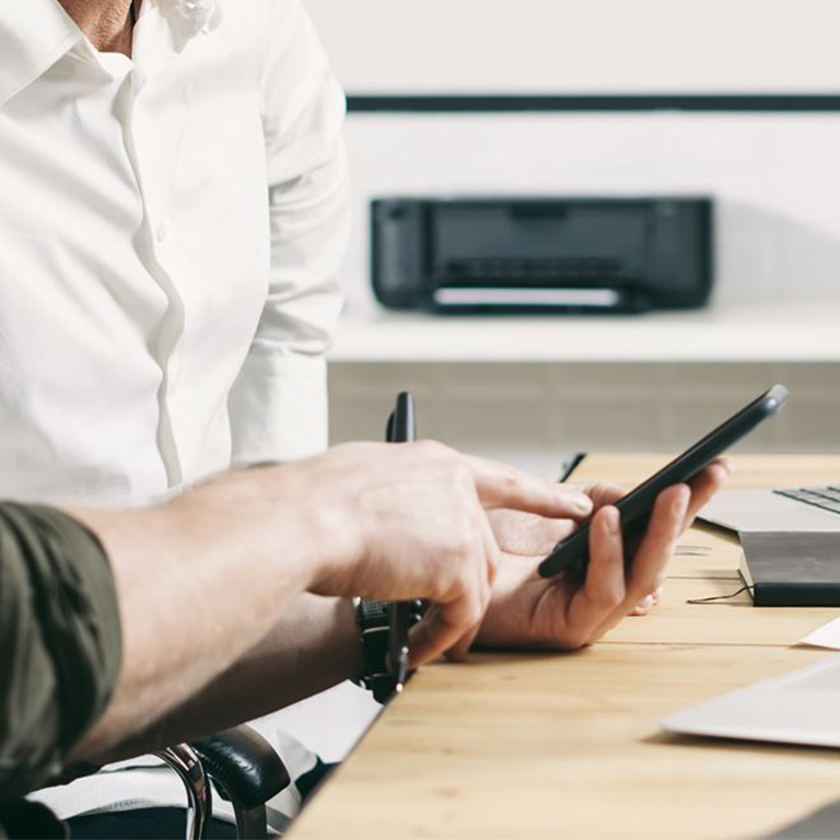 Concept of business people meeting process. Bearded young man holding mobile phone and touching screen. Adult businessman working together with partner. Horizontal wide, blurred background