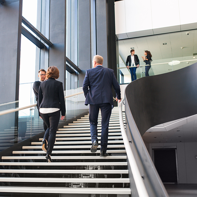 Modern business people walking on stairs in glass hall of office building