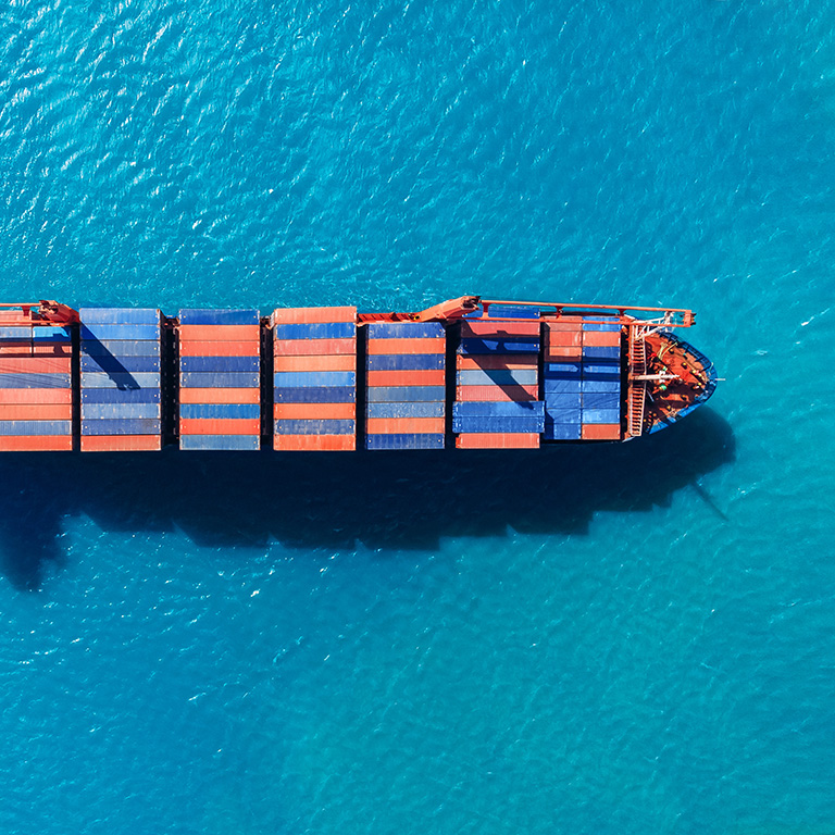 Cargo ship with containers against the blue sea, top view aerial. Logistics delivery concept.