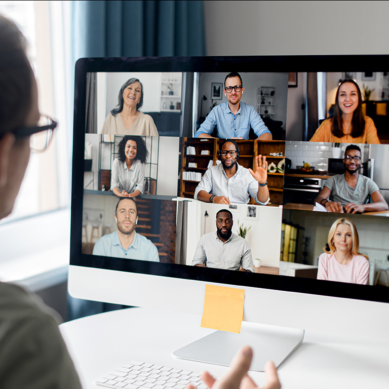 View from back above male shoulder on the laptop with diverse employees, coworkers on the screen, video call, online meeting. App for video conference with many people together