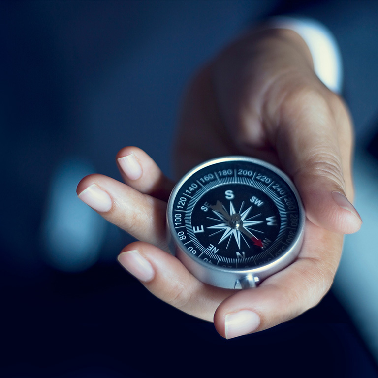close up of hand holding a compass with blue background: Business navigate recovery, Abstract, The compass navigate for businessmen to resume business growth in the economic crisis, Rethink, Reinvent and Recover