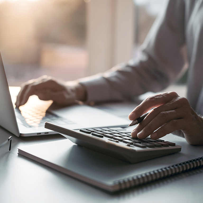 Close-up of a person using calculator and laptop, businessman working at home, finance, tax and accounting concept.