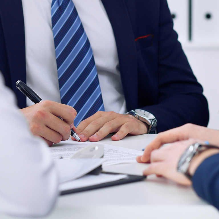 Business people at a meeting in the office. Focus on person signing contract or financial papers.