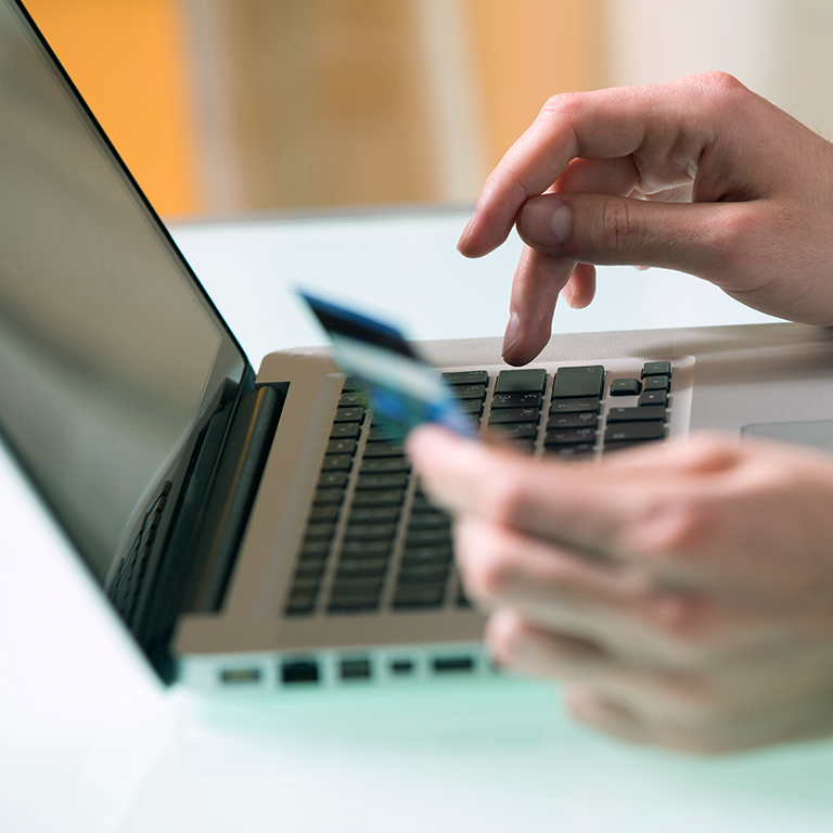 Man's hand entering data using laptop while holding a credit card in the other hand - Online banking concept