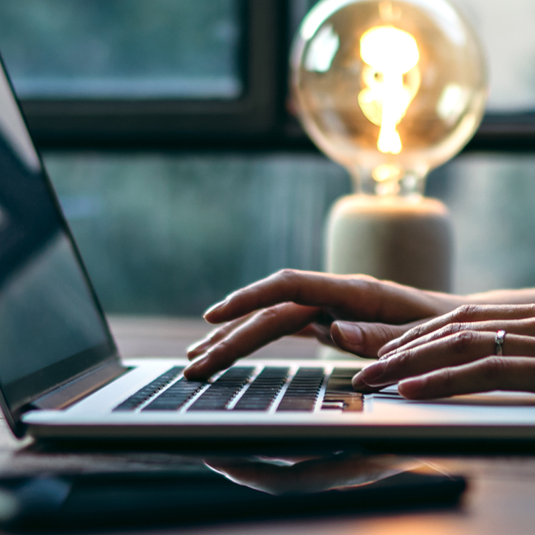 Young woman working with a laptop. Female freelancer connecting to internet via computer. Blogger or journalist writing new article. Close-up of female hands typing on keyboard