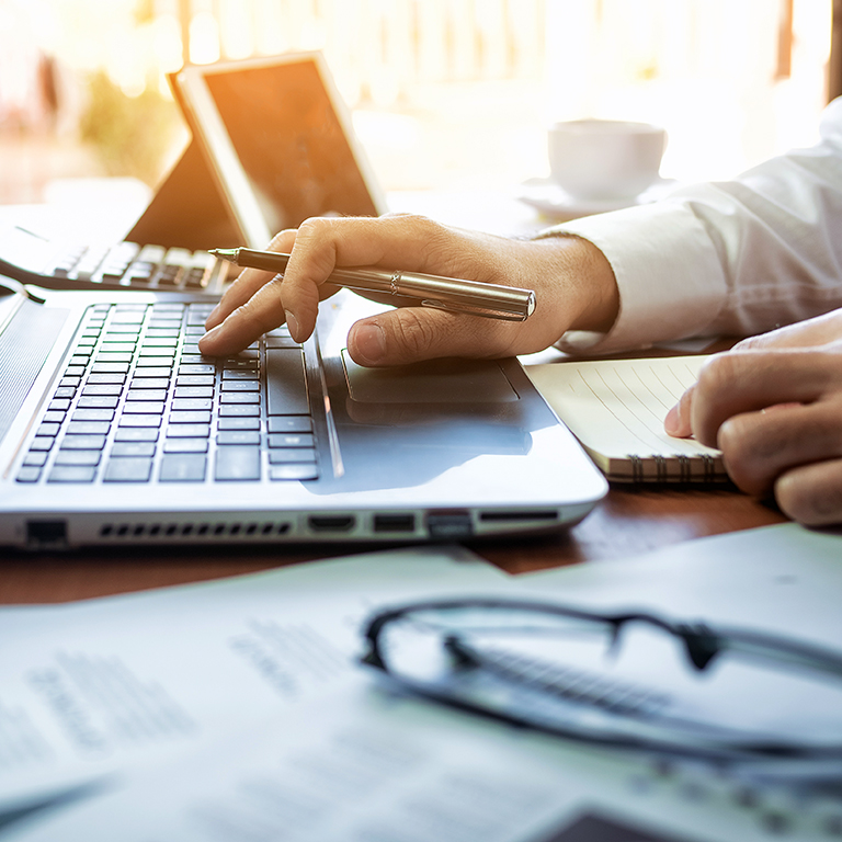 Close-up of a person working on laptop, analysing data.