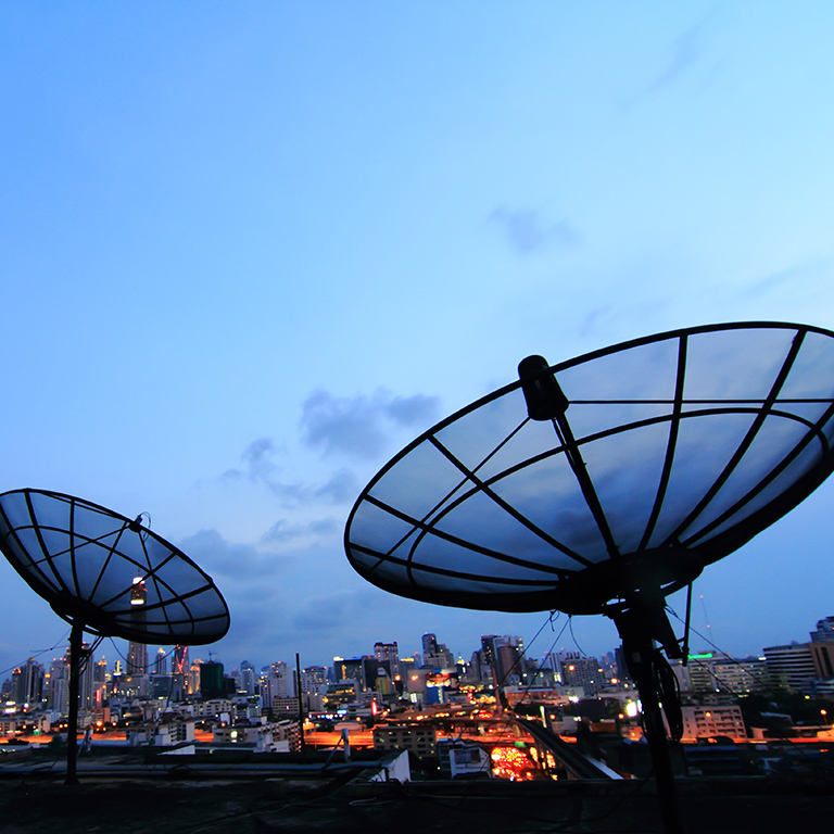black antenna communication satellite dish over sunset sky in cityscape