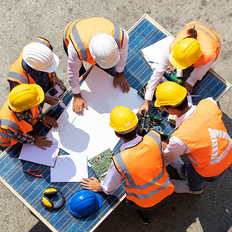 Group of professional engineering people wearing hardhat safety helmet meeting with solar photovoltaic panels discussion in new project