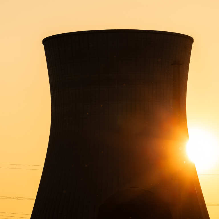 Cooling tower stands against sunset in power plant