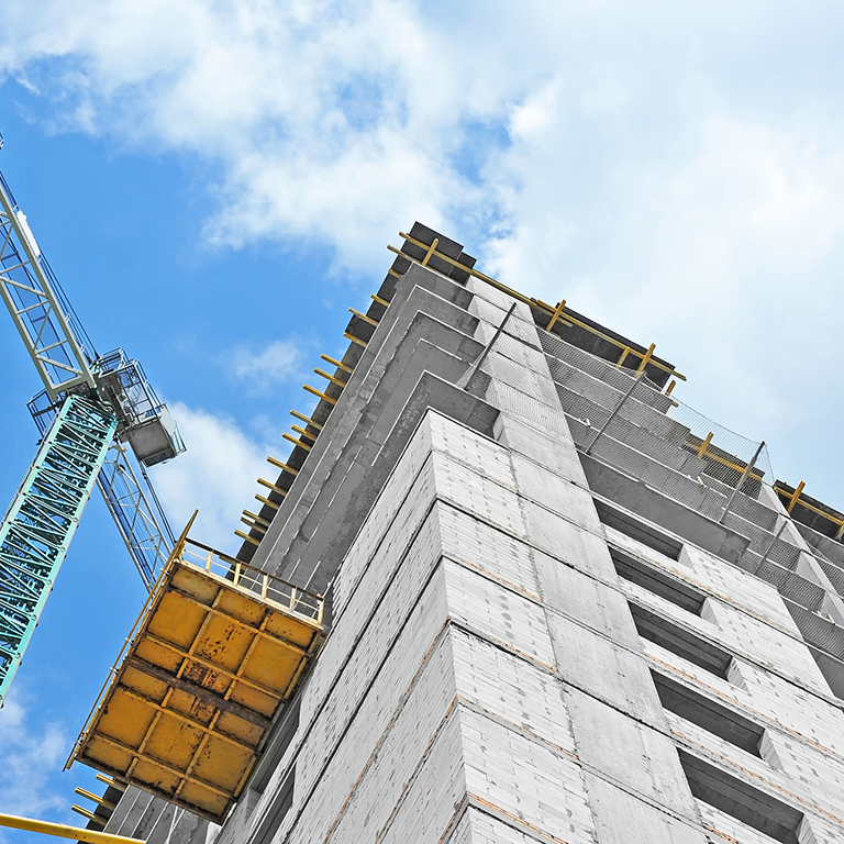 Crane and building construction site against blue sky