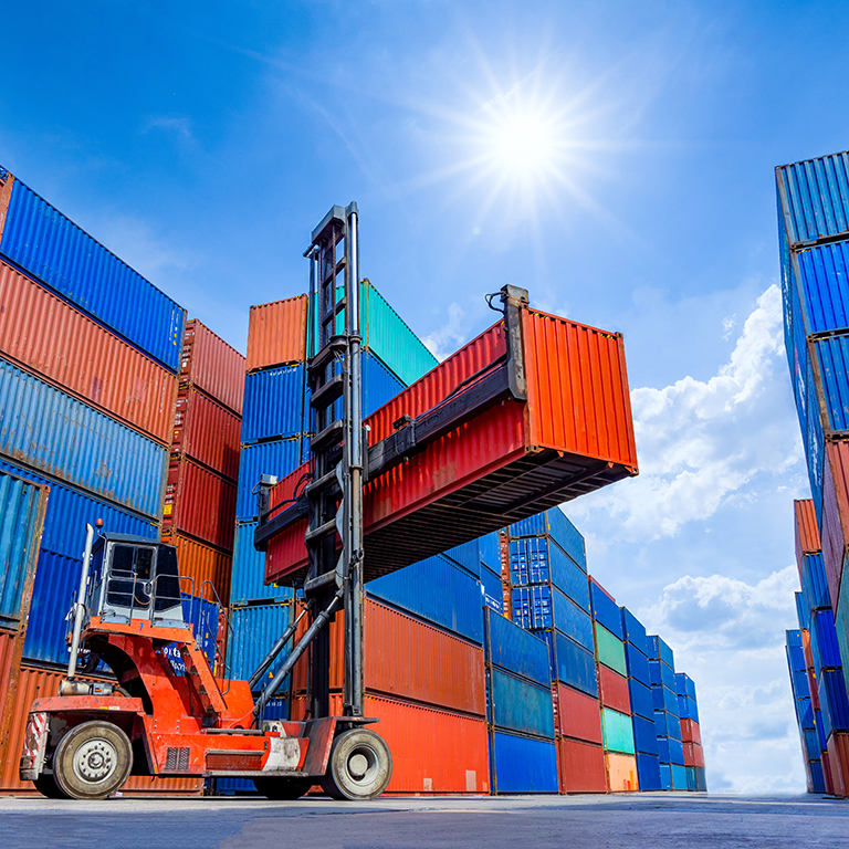 Container stacker crane lifting up stacking container box in shipping yard.