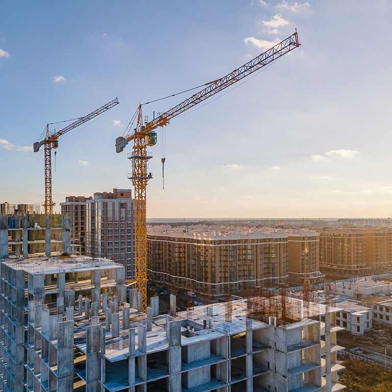 Cranes on the construction site surrounded by new real estates. Scenic aerial photo of growing city districts.