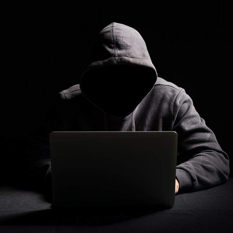 Hacker working on laptop in the dark