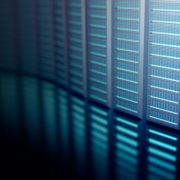 Rows of data storage units are present in a large facility at night. The lights from the units create a blue glow, showing the technology in use. The setting highlights the scale of storage.