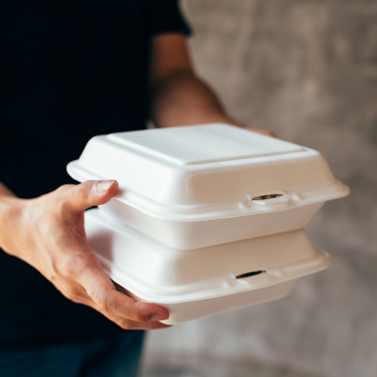 Close-up of delivery man handing a slack of foam lunch box - Foam box is toxic plastic waste. Used for recycling and environment saving concept