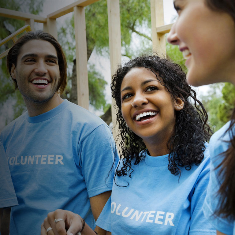 Diverse group of mixed-gender volunteers smiling in an outdoor setting