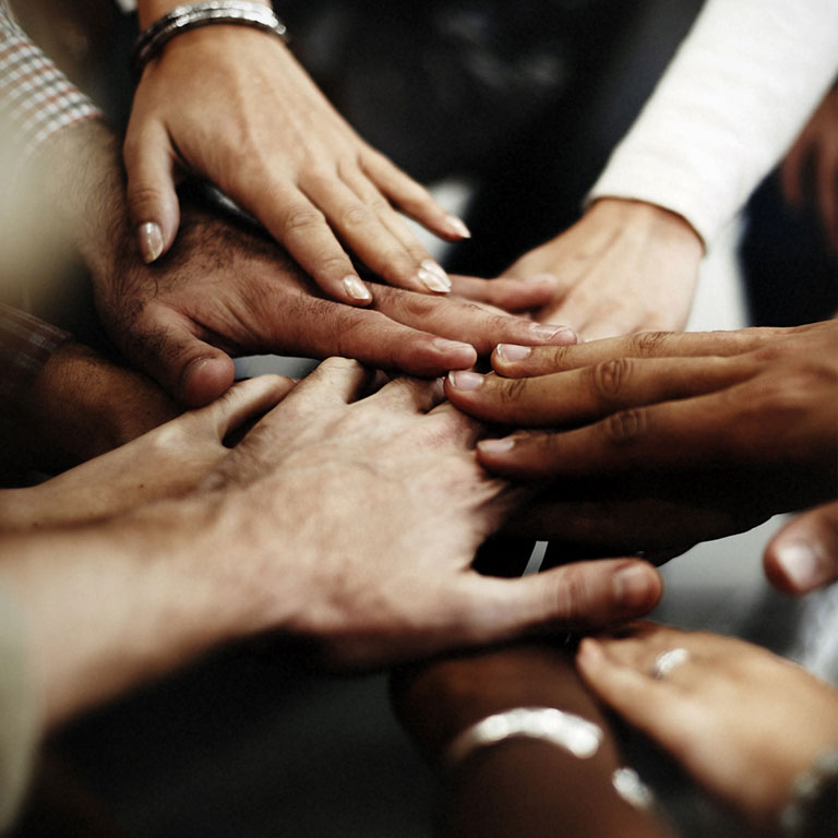 A diverse, mixed gender team stacking hands together