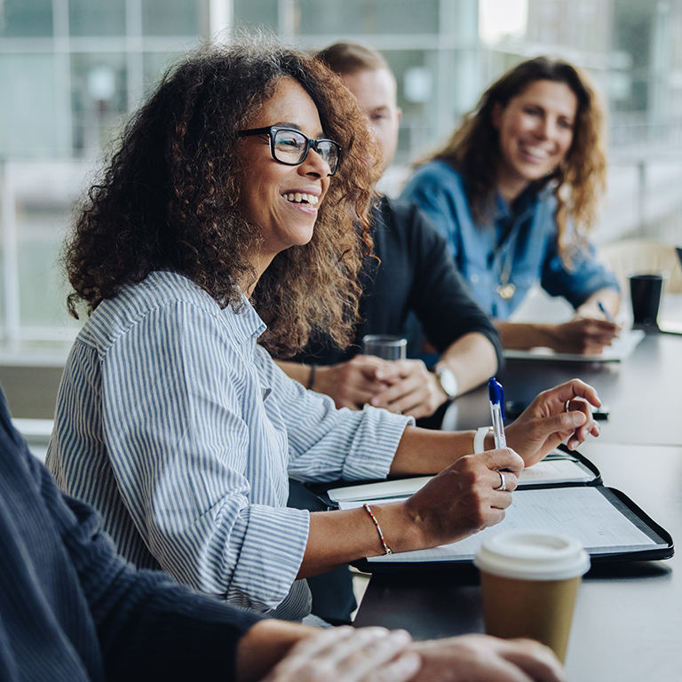 Multi-ethnic business people smiling during a meeting in conference room. Team of professionals having meeting in boardroom.