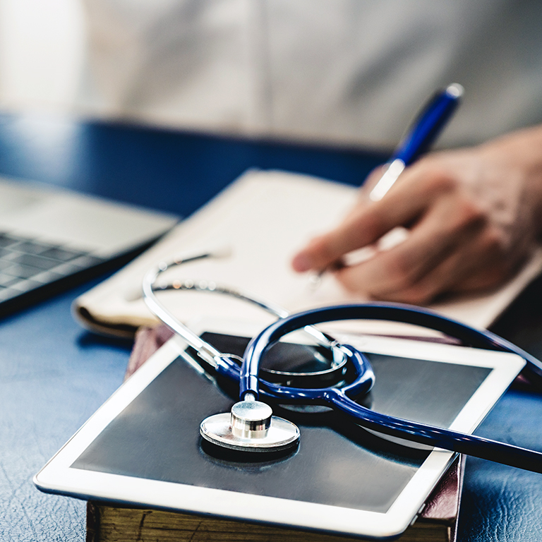 Doctor working on a computer in hospital office with paperwork. Medical healthcare concept.