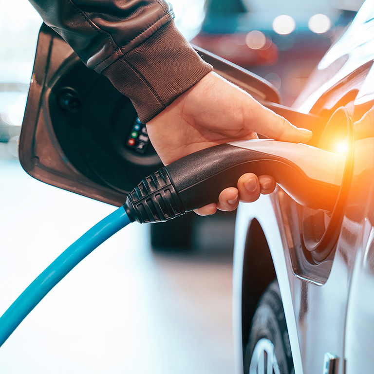 Closes up Human hand is holding Electric Car Charging connect to Electric car