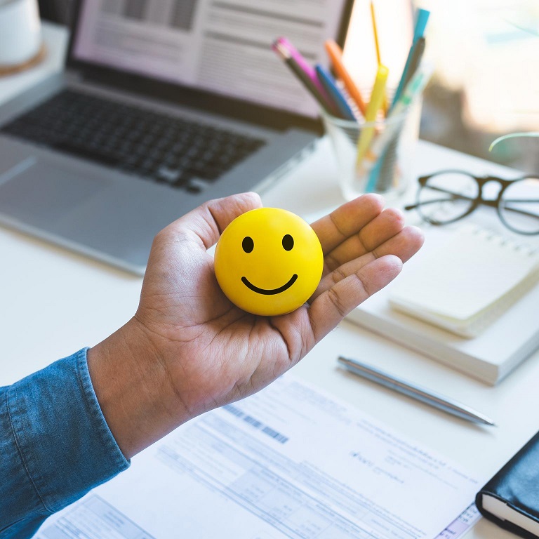 Emoticon ball on male hand on work table. Happy life concepts.