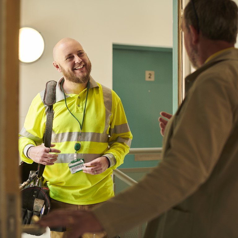 Engineer in hi-viz at front door of flat